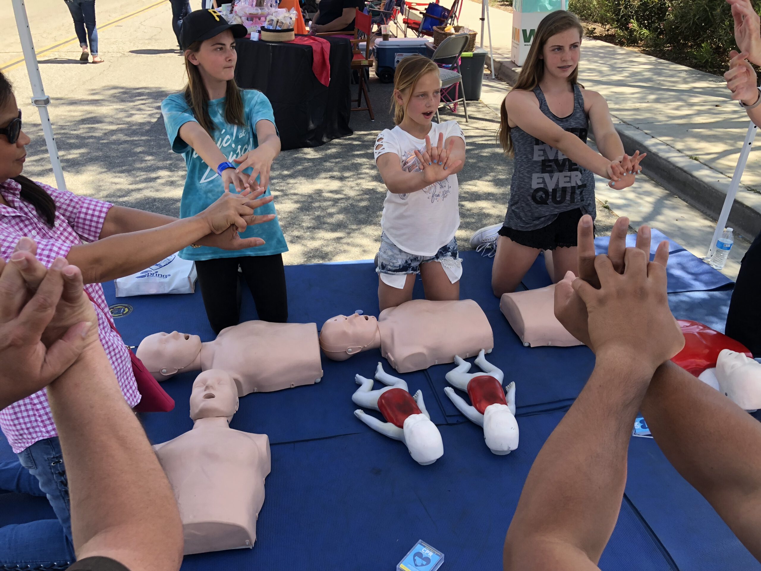 Three young girls demonstrating the correct hand technique for hands only CPR