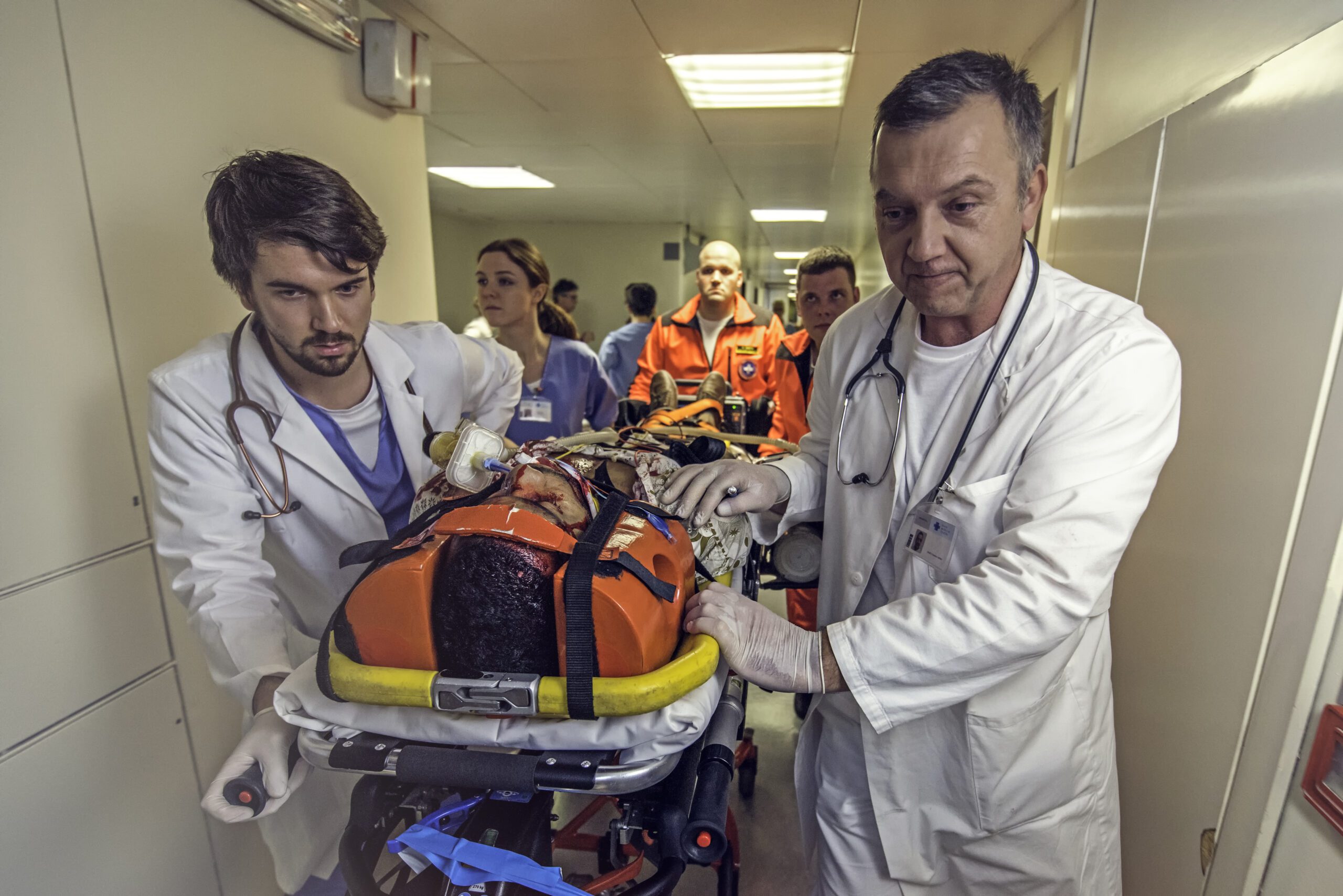 Paramedics, doctors and nurse pulling hospital trolley with injured patient.